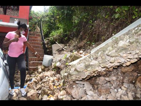 Juliet Clarke of Lindo’s Gap in rural St Andrew points to her retaining wall that collapsed after water from the main road eroded her land, resulting in the destruction of the wall and damaging the stairway of her two-storey house.