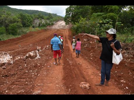 In this July 31 photograph, residents of Red Berry in Manchester walk along the excavated area that will soon be transformed into the May Pen to Williamsfield leg of the South Coast Highway.