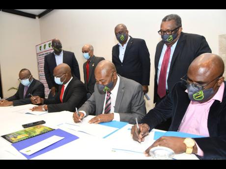 Seated from left: Donovan White, president of Waterhouse FC; Paul Christie, team manager of Dunbeholden FC; Michael Ricketts, president of Jamaica Football Federation (JFF); and Dalton Wint, general secretary of JFF, sign a memorandum of understanding rela