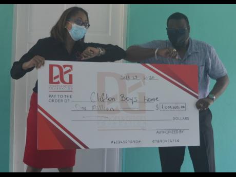 The Reverend Hartley Perrin (right), board chairman of the Clifton Boys’ Home in Darliston, Westmoreland, accepts a $1-million donation towards rebuilding the facility from Stephannie Coy, operations manager at the Desnoes & Geddes Foundation, during a m