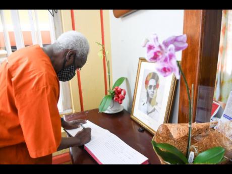 Former Prime Minister P.J. Patterson signs the condolence book for the late D.K. Duncan at the People’s National Party headquarters on Tuesday.
