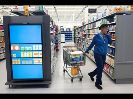 A customer pulls her shopping cart past an information kiosk at a Walmart Neighborhood Market, on April 24, 2019, in Levittown, NY. Kiosks and signs throughout the store keep customers informed that they are shopping in an artificial intelligence factory.
