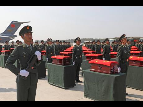 In this photo released by Xinhua News Agency, Chinese honour guards escort caskets containing the remains of Chinese soldiers killed in the 1950-53 Korean War on their return to China from South Korea at the Taoxian international airport in Shenyang, north