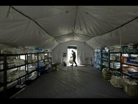  In this March 2020, file photo a US Army soldier walks inside a mobile surgical unit being set up by soldiers from Fort Carson, Col, and Joint Base Lewis-McChord (JBLM) as part of a field hospital inside CenturyLink Field Event Center, in Seattle. Militar