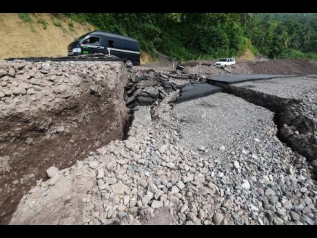 A minibus traverses past the collapsed roadway between Broadgate and the Westmoreland Bridge on Tuesday. Heavy rainfall has been blamed by local authorities for the damage but the National Works Agency has acknowledged that that section of the corridor had