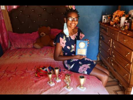 Shanique McKenzie shows off her awards at her humble home in Blue Hole, Bellas Gate.