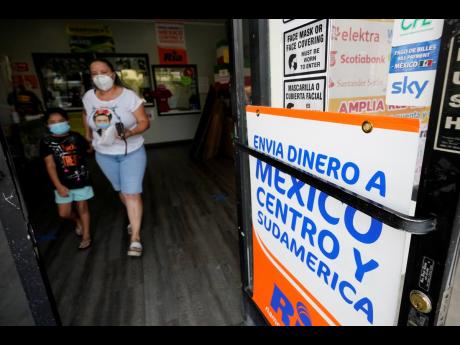A woman leaves a store offering remittance services to Mexico and Central America on Friday, September 11, in San Diego. Mexican workers have confounded economists by sending home huge amounts of money during the coronavirus pandemic. Experts had predicted