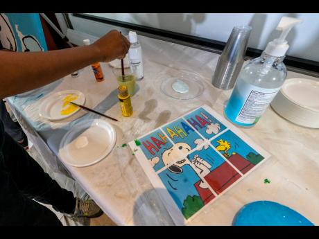 Jesse McCarty, 14, cleans his brush next to a diagram of a ‘Peanuts’ mural he is helping to paint that will be placed in the outpatient paediatric floor of One Brooklyn Health at Brookdale Hospital.