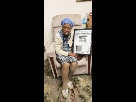 Beautilyn Carvey poses with a framed front page of The Gleaner featuring coverage of the Kendal train crash in 1957. 