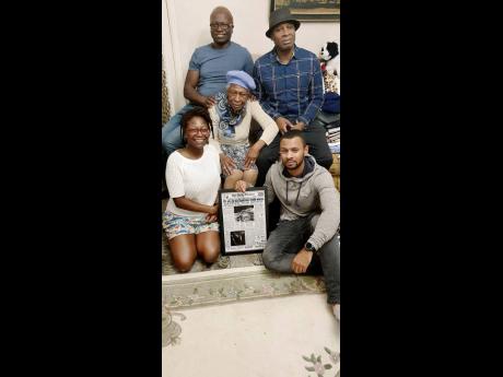Beautilyn Carvey (centre), surrounded by her family Janet, Brian, Frank and his son, Rohan, posing with a framed copy of the Gleaner front page of the Kendal crash at a family gathering in England.