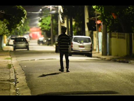 A lone figure walks along Alexander Road in Whitfield Town, Kingston, more than an hour after a 6 p.m. curfew was imposed in the community on Tuesday. Whitfield Town and Waterford, St Catherine, will face tougher restrictions on movement and public gatheri