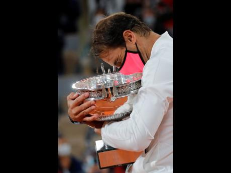 Spain’s Rafael Nadal clings to his trophy as he celebrates winning the final match of the French Open tennis tournament against Serbia’s Novak Djokovic in three sets, 6-0, 6-2, 7-5, at the Roland Garros stadium in Paris, France, yesterday.