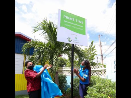 Michelle-Ann Letman (right), manager, public relations and corporate social responsibility, Sagicor Group Jamaica, unveils a sign at the Prime Time Early Childhood Institution in Denbigh, Clarendon,  alongside principal of the school, Eda Golding.