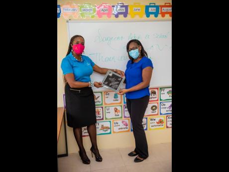 Carla Drummond (left), Sagicor Bank branch manager, Savanna-la-Mar, accepts a plaque as a token of gratitude from principal of Petersville Early Childhood Institution, Simone Quest-Osullivans, in a new classroom built by the Sagicor Foundation as part of  