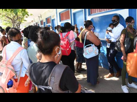 Residents gather outside a health centre with few of them wearing masks and none practising social distancing, despite a spike in the coronavirus cases in St Catherine.