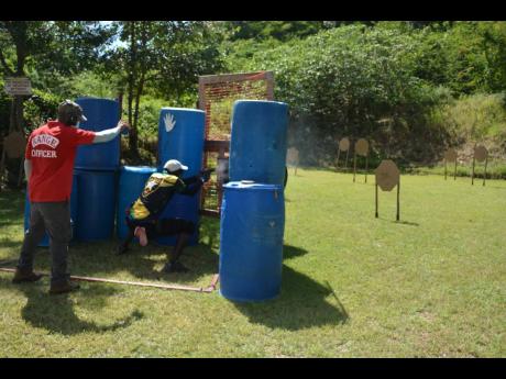 
A shooter competes in the recent fundraising shooting competition, while a ranger officiates at the Negril Tactical Shooting Range.