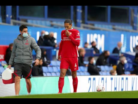 Liverpool's Virgil van Dijk leaves the match with an injury during the English Premier League match between Everton and Liverpool at Goodison Park stadium, in Liverpool, England, Saturday, Oct. 17, 2020. (Cath Ivill/Pool via AP)