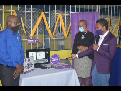 Chris Dehring (right), director and chief executive officer of the ReadyTV digital broadcast television network, demonstrates how the network’s system works at the Glendevon Primary and Junior High School in St James. Looking on are Education Minister Fa