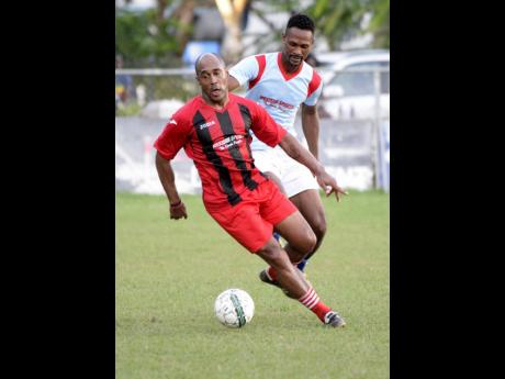 Former national footballer Wolde Harris turns away from his marker during their Bob Marley One Love exhibition football match at Winchester Park in Kingston on Monday, October, 15, 2018.