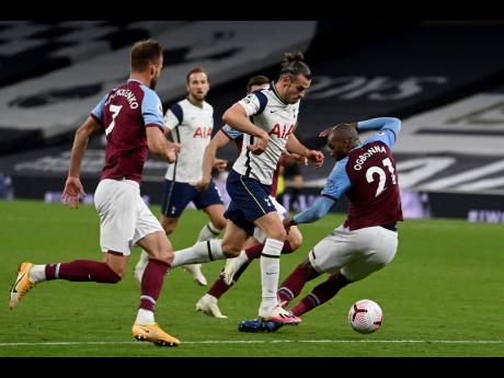 Tottenham’s Gareth Bale (centre) carries the ball around West Ham’s  Angelo Ogbonna (right) during their English Premier League match at the Tottenham Hotspur Stadium in London, England, yesterday.