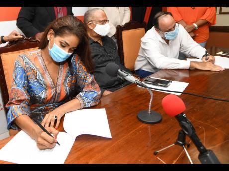 People’s National Party presidential contenders Lisa Hanna and Mark Golding signing a code of conduct for the election campaign last week as party President Dr Peter Phillips looks on.