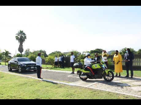 A police outrider escorts a dignitary inside the National Heroes Park in Kingston on Monday, as State Minister Alando Terrelonge, Minister Olivia ‘Babsy’ Grange and members of the constabulary force look on.