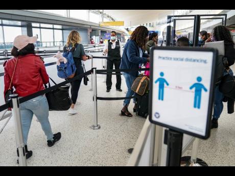 US Transportation Security Administration personnel and travelers observe COVID-19 transmission prevention protocols as acrylic dividers are employed to further protect staff working a Terminal 5 security checkpoint at John F. Kennedy International Airport