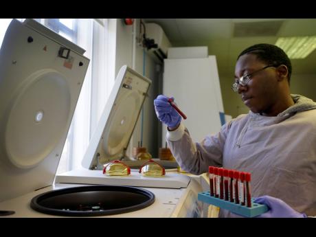 Leon McFarlane, a research technician, uses a centrifuge on blood samples from volunteers in the laboratory at Imperial College in London, Thursday, July 30, 2020. Imperial College is working on the development of a COVID-19 vaccine.