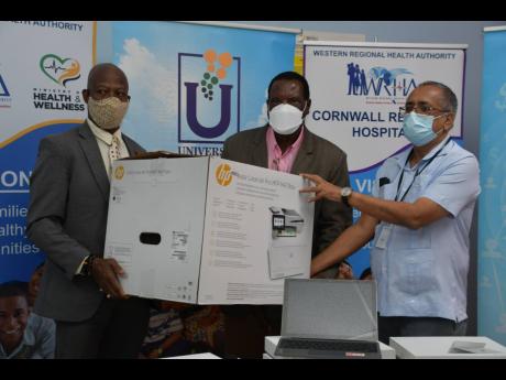 Mayor of Montego Bay, Councillor Leeroy Williams (centre), and clinical coordinator at the Cornwall Regional Hospital in St James, Dr Delroy Fray (right), representing the Western Regional Health Authority (WRHA), accept a donation of  information and comm