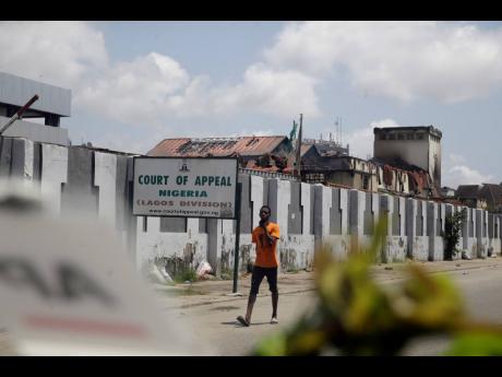 A man walks past a burnt Court of Appeal building in Lagos, Nigeria, Thursday October 22, 2020. Lagos streets were empty and shops were shuttered Thursday, as residents of Nigeria's largest city obeyed the government's curfew, stopping the protests against