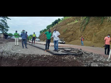 Government Minister Everald Warmington (centre, right) and St Mary South Eastern Member of Parliament Dr Norman Dunn discussing aspects of design crafted by NWA technical personnel for the reconstruction of the collapsed roadway at Chovey in St Mary during