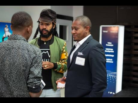 
INDIGGO Conference: Reggae artiste Protoje (centre) and Minister of Agriculture and Fisheries Floyd Green (right) speak to a patron at the virtual arthouse exhibition at last year’s staging of the INDIGGO Conference.