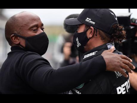 Mercedes driver Lewis Hamilton (right) of Britain is congratulated by his father Anthony Hamilton after his record-breaking win during the Formula One Portuguese Grand Prix at the Algarve International Circuit in Portimao, Portugal, yesterday.