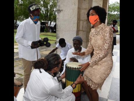 Imani Duncan-Price, daughter of the late Dr D.K. Duncan, plays the drum alongside members of Akwaaba and Mystice Revelation as they  performed outside the University Chapel in Mona during Duncan’s funeral on Sunday. 