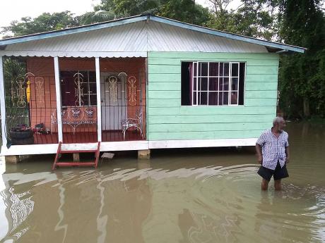 Gladstone Wollery, a resident of Three Miles River in Westmoreland, up to his knees in floodwaters that covered several yards in the community on Sunday.