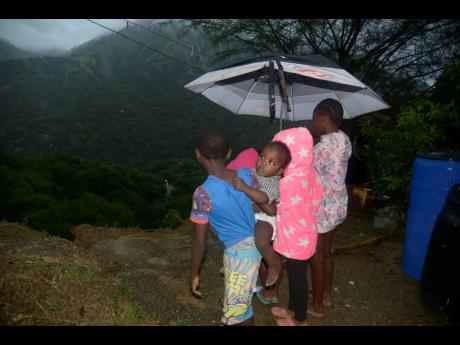 More than 20 children, among a family of almost 60 living in Lindo’s Gap, St Andrew, peer over a precipice after heavy rains swept away their backyard on the weekend. 