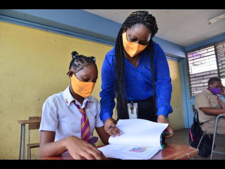 Grade 11 coordinator at Pembroke Hall High, Jodi-Ann Carnegie, assists fifth-form student Tasheika Messam with her work on Monday, June 8, 2020. Schools reopened for sittings of regional examinations ahead of the summer holidays. Education Minister Fayval 