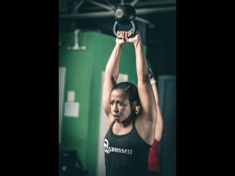 Coke does the kettle bell swing at Fitness 876 prior to her diagnosis. A CrossFit enthusiast for the past five years, she is eager to get back into the swing of things.