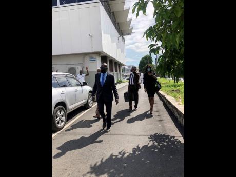 Ruel Reid (foreground) leaving the parish court in Kingston yesterday. 