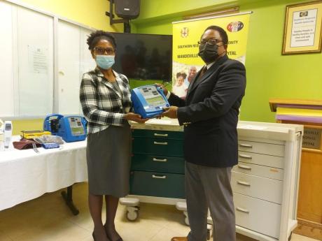 Health ministries director at the Central Jamaica Conference, Deon Henry, hands over a vital-signs machine to chief executive officer at the Mandeville  Regional Hospital, Alwyn Miller. 