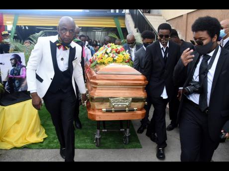 Peter Perry (left) CEO of Perry’s Funeral home leads the  pallbearers has they take the  casket carring the remains of the late Fredrick “Toots” Hibbert to a hearse that will take his body to  Dovecot Memorial Park on Thursday where he will be buried