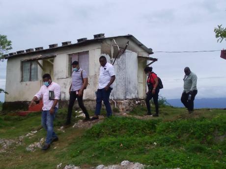 Police investigators at the home where two brothers were shot dead in Good Hope, St Elizabeth, yesterday.