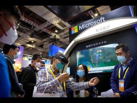 A visitor wearing a face mask uses augmented reality eyewear at a display from Microsoft at the China International Import Expo in Shanghai.