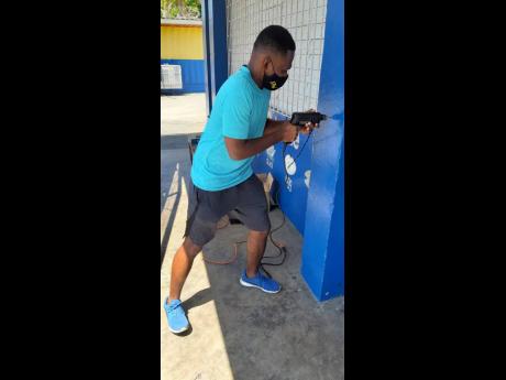 Andre Barnaby installing hand sanitiser dispensers at the Windward Road Primary School in Central Kingston