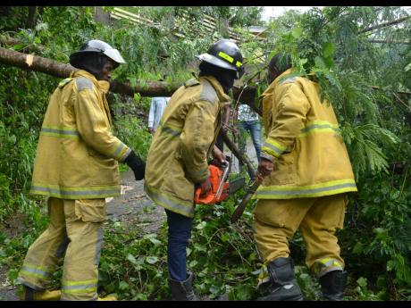Firemen from Half-Way Tree Fire Station prepare to clear a blocked section of the Gordon Town main road on Sunday.