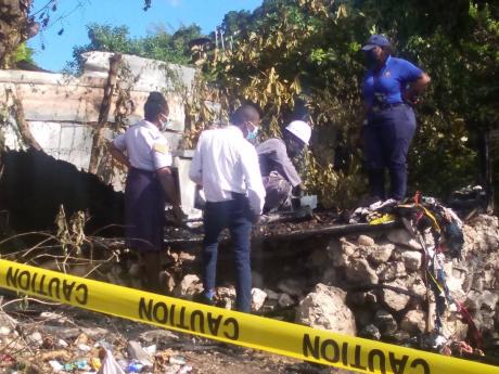 Police and fire investigators sift through the charred rubble after a five-year-old boy was burnt to death in a one-bedroom board house in Flankers, St James, yesterday.