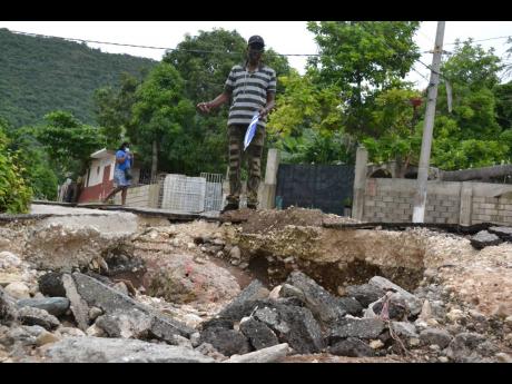 Phillip Edwards shows a canyon-type hole in the rain-ravaged Balkan Avenue in Harbour Heights, east Kingston. 