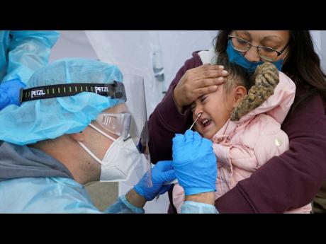 Kim Tapia holds her three-year-old granddaughter Amariah Lucero as she is tested at the Utah National Guard's mobile testing site for COVID-19 in Salt Lake City. The US has recorded about 10.3 million confirmed infections, with new cases soaring to all-tim