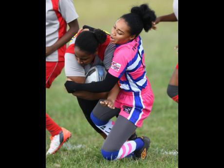 York Castle’s Serena Walcott (left) holds onto the ball while being taken down by August Town Pink Pumas’ Alexis Dawkins in their Jamaica Rugby Football Union tournament held at the GC Foster College of Physical Education and Sport on Saturday, January