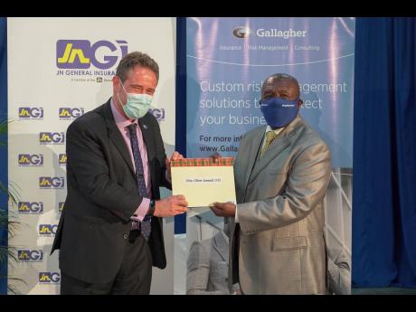 
Oliver Samuels (right), the Caribbean Community of Retired Persons Living Legacy Award honouree, receives a gift from Chris Hind, general manager, Jamaica National General Insurance, co-sponsors of the award ceremony held on Wednesday. 